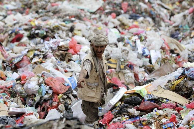 A man collects recyclable cans and bottles at a garbage disposal site near Sanaa