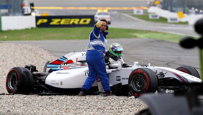 A track marshall gives a thumb up as Williams Formula One driver Felipe Massa of Brazil climbs out of the wreckage of his car after crashing in the first corner after the