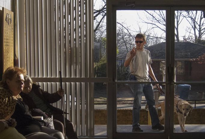 Visually impaired student Curtis Norton, assisted by his guide dog, knocks on an entrance door to the World Services for the Blind in Little Rock, Arkansas January 6, 2013. The blind and the visually impaired, whose sight is not sufficient to walk safely in public environments, use the help of a cane or a guide dog. The WSB is a rehabilitation center for the blind or visually impaired which offers life skills and career training programs designed to help those enrolled achieve sustainable independence. Picture taken on January 6, 2013. REUTERS/Gaia Squarci (UNITED STATES - Tags: HEALTH EDUCATION ANIMALS SOCIETY) Published: Dub. 26, 2013, 2:17 odp.