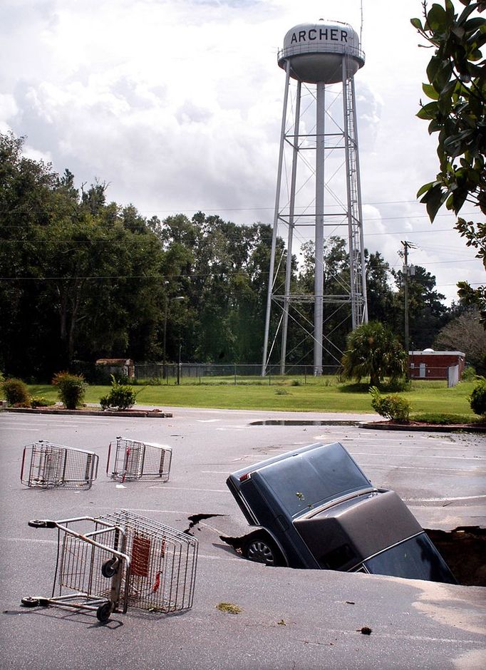 In this Sept. 7, 2004 file photo, a sinkhole approximately 10 feet deep swallowed this automobile in the parking lot of Hitchcocks Foodliner in Archer, Fla. (AP Photo/The Gainsville Sun, Jim Matthews)