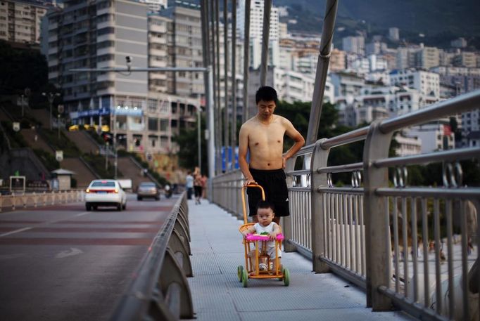 A man walks with his son on a bridge over the Yangtze River in Badong city, 100km (62 miles) from the Three Gorges dam in Hubei province in this August 8, 2012 file photo. China relocated 1.3 million people during the 17 years it took to complete the Three Gorges dam. Even after finishing the $59 billion project last month, the threat of landslides along the dam's banks will force tens of thousands to move again. It's a reminder of the social and environmental challenges that have dogged the world's largest hydroelectric project. While there has been little protest among residents who will be relocated a second time, the environmental fallout over other big investments in China has become a hot-button issue ahead of a leadership transition this year. Picture taken on August 8, 2012. To match story CHINA-THREEGORGES/ REUTERS/Carlos Barria/Files (CHINA - Tags: POLITICS ENVIRONMENT BUSINESS ENERGY) Published: Srp. 22, 2012, 8:36 odp.