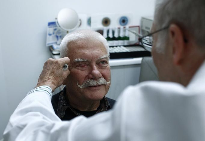 Ocularist Gerhard Greiner compares a glass eye example with the eye of patient Helmut Sechser in his medical equipment shop in Munich December 11, 2012. Greiner produces individual hand glass-blown human eye prostheses for people who have lost an eye or eyes due to a trauma, illness or accident. Each glass eye takes about one hour to make, with constant reference to the patient for the right colour and for detailed drawing of the veins. A bespoke glass eye prostheses cost about 350 euros (US $457). A typical modern glass eye is a hollow half sphere that fits over the non-working eye, if it is still there. Otherwise it goes over a ball that has been surgically implanted into the eye socket and attached to the eye muscles. Picture taken on December 11. REUTERS/Michaela Rehle (GERMANY - Tags: HEALTH SOCIETY) Published: Pro. 13, 2012, 12:34 odp.