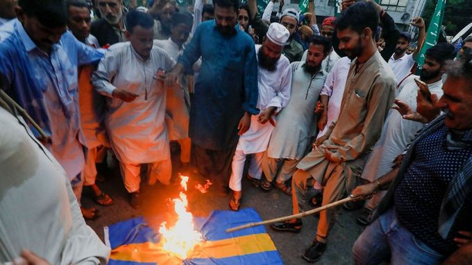 Lidé v pákistánském Karáčí pálí švédskou vlajku při protestech proti pálení koránu iráckým uprchlíkem ve Stockholmu.