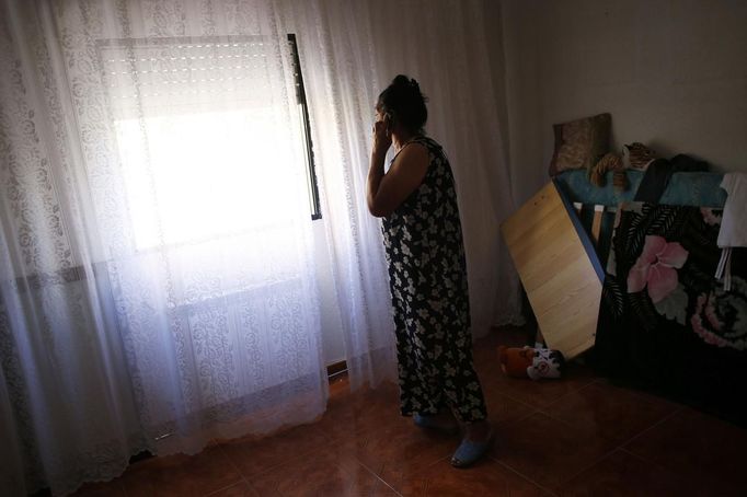 Pilar Amador talks on the phone as she looks out of the window before learning that her eviction by the Municipal Housing and Land Company (EMVS) was postponed in Madrid June 14, 2013. Amador currently lives with one of her sons and three of her grandchildren in a social rent flat in Madrid, where most of her children and grandchildren were raised in since she moved there in 1998. The family, where most of the adults don't hold a steady job, was sent an eviction notice at the beginning of the month. The eviction was finally postponed until September after negotiations between Amador's lawyer and the help of anti-eviction activists. REUTERS/Susana Vera (SPAIN - Tags: SOCIETY REAL ESTATE BUSINESS) Published: Čer. 14, 2013, 4:40 odp.