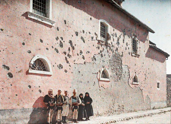 Lidé před  poškozenou zdí františkánského kláštera v Albánii. Rok 1913