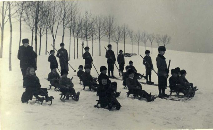 Děti na sáňkách, dospělí na lyžích, kolem roku 1900.