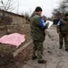 Důstojníci stojí vedle těla obyvatele, který byl zabit nedávným ostřelováním v Doněcku.