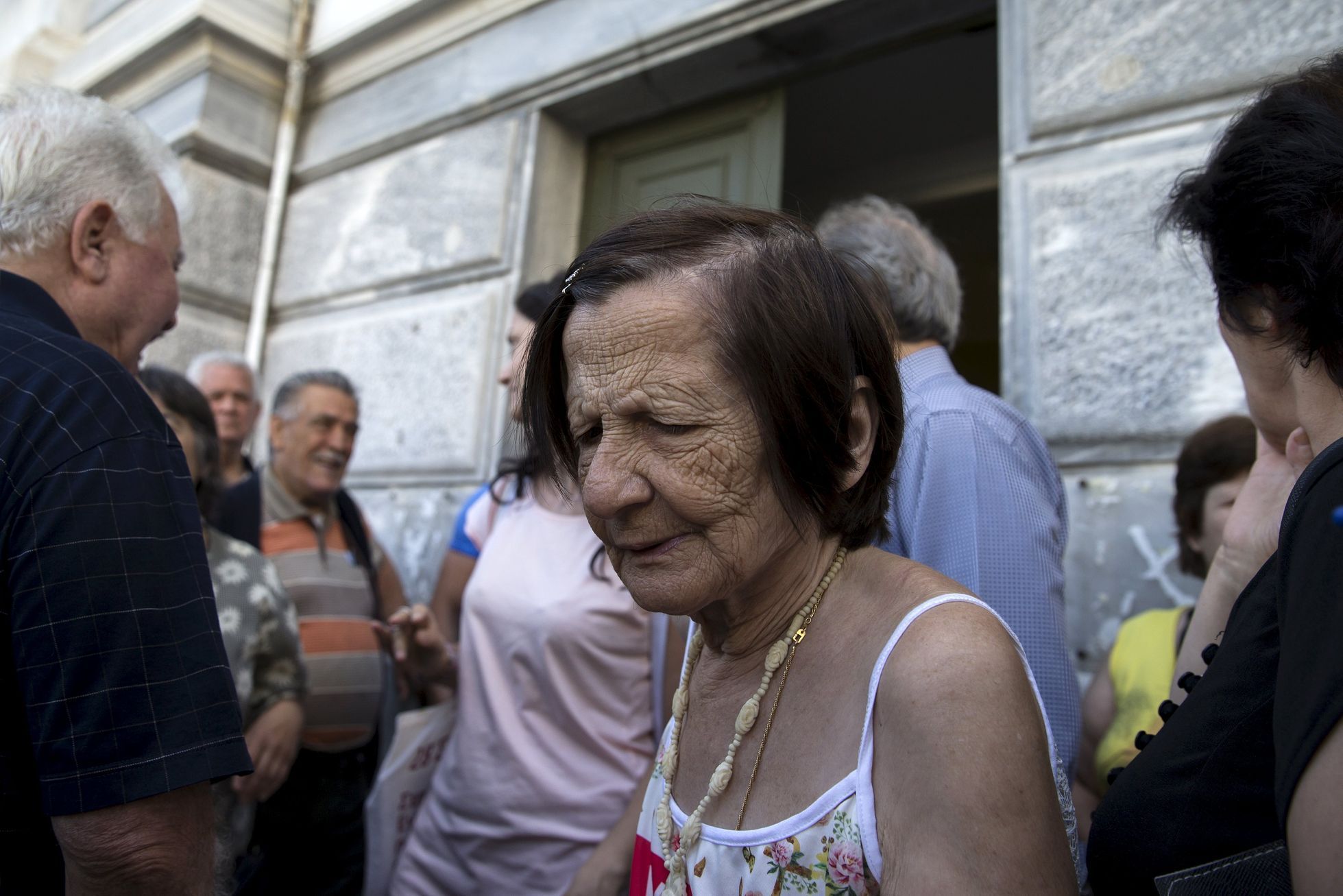 People, most of them pensioners, gather outside a closed National Bank branch at the bank's headquarters in Athens