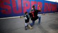 Fanoušek amerického fotbalu a jeho syn napodobuje gesto Colina Kaepernicka, jednoho z "klečících fotbalistů", na jeho podporu