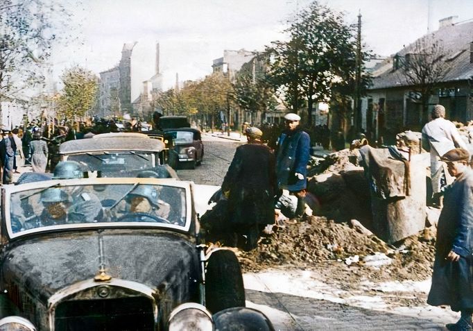 Německá vojska projíždějí kolem barikád ve Varšavě po jejím obléhání, 1939. Kolorovaný snímek