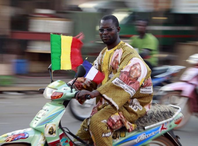 A man rides his motorbike displaying a Malian and a French flag in Bamako January 20, 2013. French troops in armoured vehicles advanced on Sunday towards a central Malian town abandoned by Islamist rebels after days of air strikes, moving cautiously for fear of guerrilla-style counterattacks by the al Qaeda-linked fighters. REUTERS/Eric Gaillard (MALI - Tags: CIVIL UNREST CONFLICT POLITICS SOCIETY TRANSPORT) Published: Led. 20, 2013, 8:02 odp.