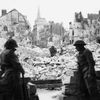 British troops keep watch across a destroyed square from a doorway of a cathedral after finally dislodging German forces from Caen