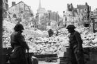 Pohled ze stejného místa na snímku z července roku 1944. Britské jednotky hlídkují na zničeném náměstí v Caen. Podle původního plánu mělo být město dobyto v prvních dnech po dni D. Spojenci zde narazili na tuhý odpor Němců a o Caen se vedla dlouhá dvouměsíční "opotřebovávací" válka.