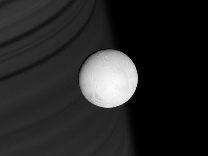 Enceladus ze vzdálenosti 291 000 kilometrů. V pozadí Saturn.