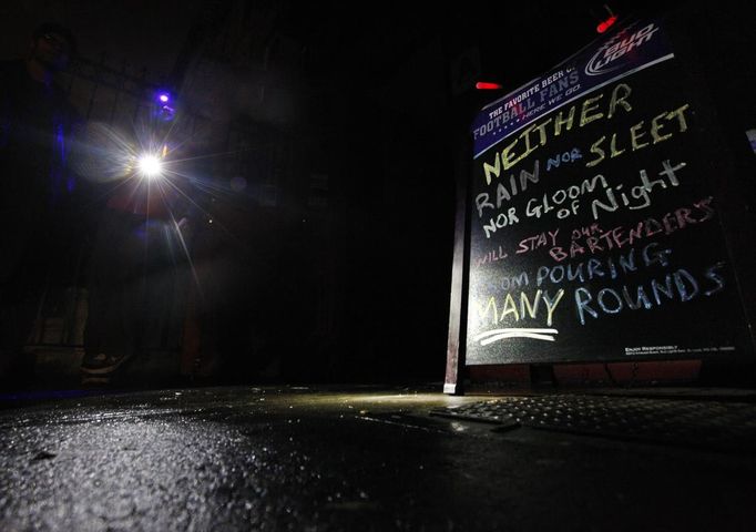 Devin Vilardi, Manager, stands with a flash light outside Professor Thom's bar that is still serving drinks even though they have no power in New York October 30, 2012. Millions of people were left reeling in the aftermath of the whipping winds and heavy rains of the massive storm Sandy on Tuesday as New York City and many parts of the eastern United States struggled with epic flooding and extensive power outages. REUTERS/Brendan McDermid (UNITED STATES - Tags: SOCIETY ENVIRONMENT DISASTER) Published: Říj. 31, 2012, 1:10 dop.