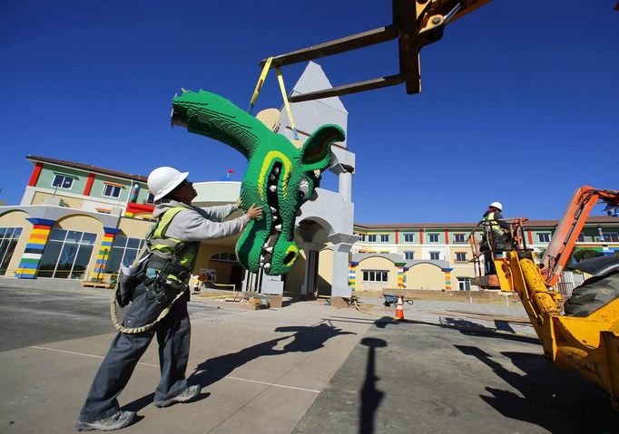 A worker helps lift a dragons head made of Lego into position as construction continues in North America's first ever Lego Hotel being built at Legoland in Carlsbad, California, January 17, 2013. The three-story, 250-room hotel will open on April 5. REUTERS/Mike Blake (UNITED STATES - Tags: SOCIETY TRAVEL) Published: Led. 17, 2013, 10:28 odp.