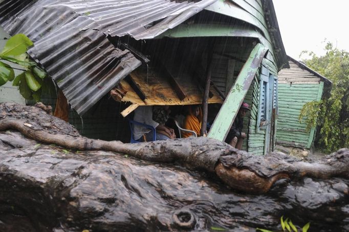 A family sits in their porch after winds from Tropical Storm Isaac brought a tree down, hitting the corner of their house, in El Habanero, Barahona province, August 25, 2012. Tropical Storm Isaac emerged over warm Caribbean waters on Saturday slightly weaker but ready to regroup after dumping torrential rains on the Dominican Republic and Haiti. REUTERS/Ricardo Rojas (DOMINICAN REPUBLIC - Tags: DISASTER ENVIRONMENT) Published: Srp. 25, 2012, 4:38 odp.