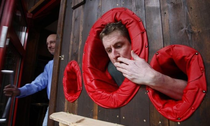 Restaurant owner Michael Windisch poses while smoking a cigarette through a special hole in the wall of his restaurant in Goslar December 29, 2007. Windisch made holes in the wall so the smokers can put their head and arms through and smoke while staying warm indoors. Germany's Lower Saxony and Baden-Wuerttemberg in the west and Mecklenburg-Western Pomerania in the east become the first states to ban smoking in public places. The other 13 have pledged to introduce bans by next year. REUTERS/Johannes Eisele (GERMANY