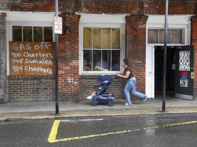 A New Orleans resident and her child run for cover past an open French Quarter bar as Hurricane Isaac approaches New Orleans, Louisiana August 28, 2012. REUTERS/Jonathan Bachman (UNITED STATES - Tags: ENVIRONMENT DISASTER) Published: Srp. 28, 2012, 8:54 odp.