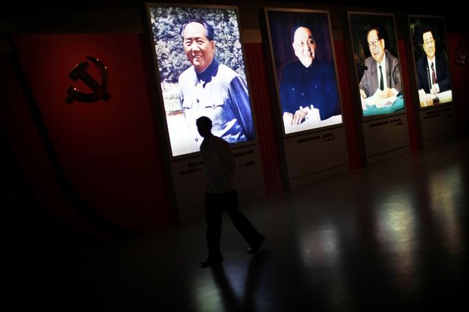 A man walks past portraits of Chinese leaders Mao Zedong (L-R), Deng Xiaoping, Jiang Zemin and Hu Jintao at the Revolution Museum in Jinggangshan, Jiangxi province, in this September 20, 2012 file photo. China's Communist Party has dramatically stepped up its training of the country's roughly 40 million party and government officials in the past decade. With public scrutiny of cadre behaviour growing via social media, the party is likely to call for continued, and deepened, cadre education at the upcoming 18th Party Congress. At the vanguard of this education drive, alongside a Central Party School in Beijing, are three "Executive Leadership Academies" which opened in 2005 for middle-ranking and senior officials in Shanghai, Yan'an and Jinggangshan. The curriculum covers Marxism, Leninism and Mao Zedong Thought, but students may also take finance courses, receive in-depth media training or role-play crisis management scenarios on everything from disease outbreaks to train wrecks. REUTERS/Carlos Barria/Files (CHINA - Tags: POLITICS SOCIETY) Published: Zář. 24, 2012, 2:15 odp.