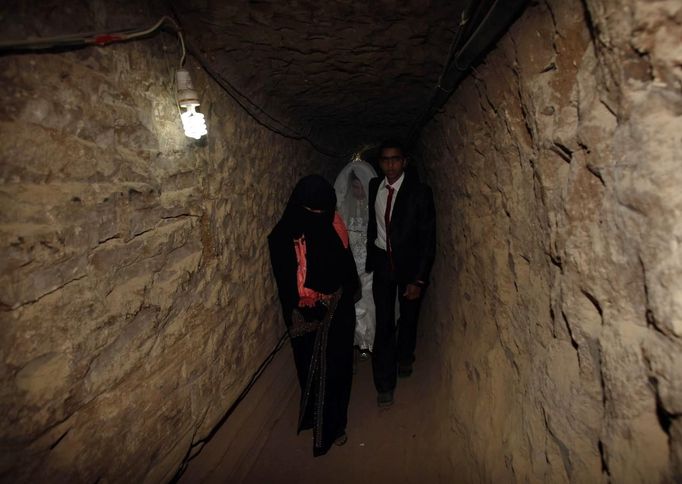 Palestinian groom Emad al-Malalha, 21, walks with Manal Abu Shanar, 17, his Egyptian bride inside a smuggling tunnel beneath the Gaza-Egypt border in the southern Gaza Strip March 21, 2013. Al-Malalha , who said that his bride was not given a permit from Egyptian authorities to enter the Gaza Strip, brought her from neighboring Egypt through a smuggling tunnel to celebrate his wedding in his native Gaza Strip. REUTERS/Ibraheem Abu Mustafa (GAZA - Tags: POLITICS SOCIETY) Published: Bře. 21, 2013, 6:22 odp.