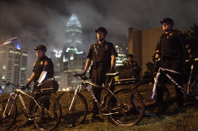 Police officers stand guard as demonstrators march during the first day of the Democratic National Convention in Charlotte, North Carolina, September 4, 2012. The demonstration was held to protest against capitalism. REUTERS/John Adkisson (UNITED STATES - Tags: POLITICS CIVIL UNREST) Published: Zář. 5, 2012, 4:26 dop.