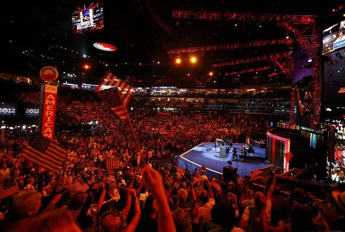 Delegates are bathed in red light as they wave flags and dance to the music as singer and songwriter Ledisi performs during the first session of the Democratic National Convention in Charlotte, North Carolina, September 4, 2012. REUTERS/Chris Keane (UNITED STATES - Tags: POLITICS ELECTIONS ENTERTAINMENT) Published: Zář. 5, 2012, 12:13 dop.