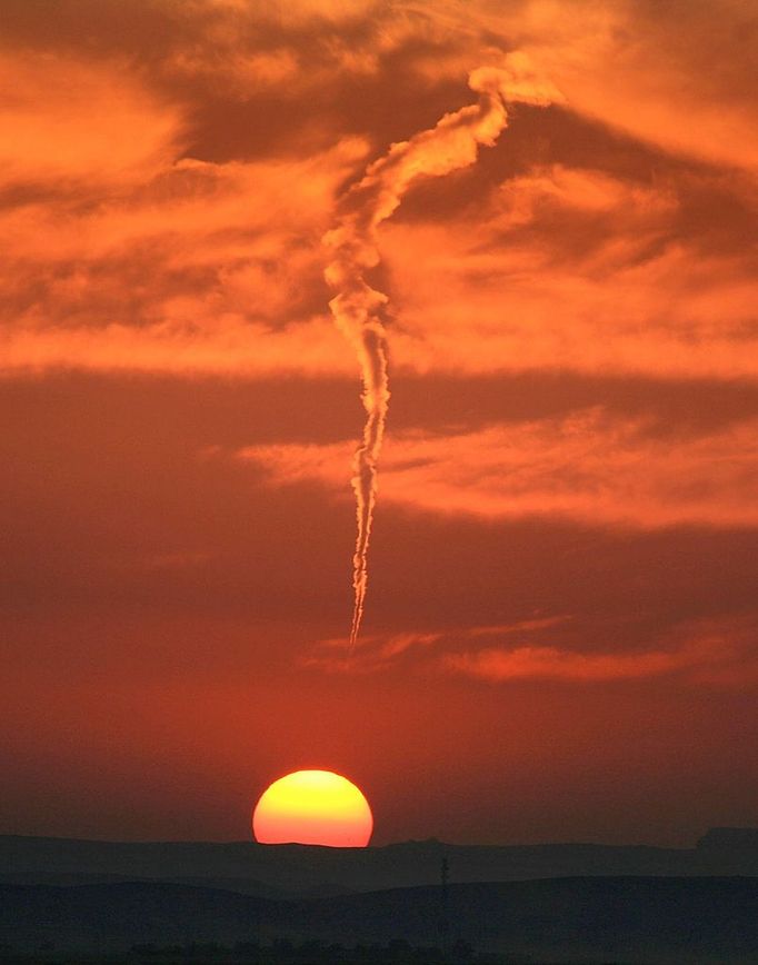 Twister with a twist in desert - (PICTURED: AEROPLANE TRAIL TORNADO IN THE SAUDI ARABIAN DESERT) - This is the moment a huge tornado appeared to be forming to rip across the middle of the desert. This stunning image appears to show the swirling wind gathering speed in front of the magnificent sunset. But while people sitting in the desert began to panic, it became clear that the super storm was in fact an AEROPLANE TRAIL. Amateur photographer Tariq Almutlaq, 45, was picnicking in the Saudi Arabian desert near Riyadh with his family, when people began to point at the sky. Fearing a tornado was imminent, they went to return to their cars - before realising that the twisted tunnel was nothing more than a jet trail.