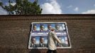 A local resident walks past a wall posted with posters in support of Sarkozy, France's President and UMP party candidate for the 2012 French presidential election