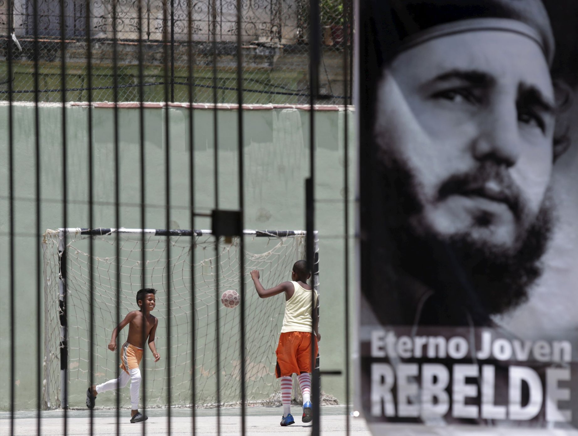 Children play soccer behind a picture of Cuba's former president Fidel Castro in Havana