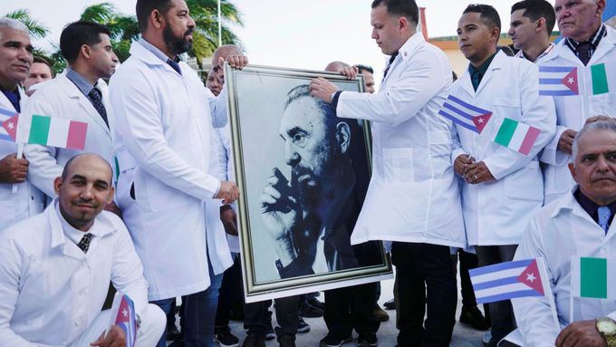 Kubánští doktoři s fotografií Fidela Castra se loučí s veřejností před cestou do Itálie.