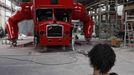 Artist David Cerny sits on a chair at a factory hall in Prague as he works on his project to transform a London bus into a robotic sculpture June 25, 2012. The bus, which Cerny hopes could become an unofficial mascot of the London 2012 Olympic Games, does push-ups with the help of an engine powering a pair of robotic arms and the motion is accompanied by a recording of sounds evoking tough physical effort. It will be parked outside the Czech Olympic headquarters in London for the duration of the Games. Picture taken June 25, 2012. REUTERS/David W Cerny (CZECH REPUBLIC - Tags: SOCIETY SPORT OLYMPICS TRANSPORT) Published: Čec. 22, 2012, 5:56 odp.