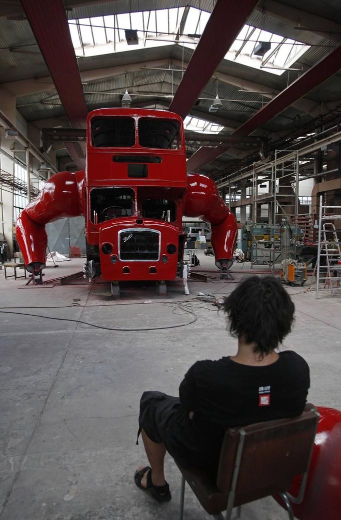 Artist David Cerny sits on a chair at a factory hall in Prague as he works on his project to transform a London bus into a robotic sculpture June 25, 2012. The bus, which Cerny hopes could become an unofficial mascot of the London 2012 Olympic Games, does push-ups with the help of an engine powering a pair of robotic arms and the motion is accompanied by a recording of sounds evoking tough physical effort. It will be parked outside the Czech Olympic headquarters in London for the duration of the Games. Picture taken June 25, 2012. REUTERS/David W Cerny (CZECH REPUBLIC - Tags: SOCIETY SPORT OLYMPICS TRANSPORT) Published: Čec. 22, 2012, 5:56 odp.