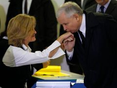 Jaroslaw Kaczyński líbá ruku předsedkyni volební komise v místnosti, kde odevzdal svůj hlas.