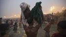 A Hindu devotee holds his belongings aloft as he attends the first "Shahi Snan" (grand bath) at the ongoing "Kumbh Mela", or Pitcher Festival, in the northern Indian city of Allahabad January 14, 2013. Upwards of a million elated Hindu holy men and pilgrims took a bracing plunge in India's sacred Ganges river to wash away lifetimes of sins on Monday, in a raucous start to an ever-growing religious gathering that is already the world's largest. REUTERS/Ahmad Masood (INDIA - Tags: RELIGION SOCIETY TPX IMAGES OF THE DAY) Published: Led. 14, 2013, 8:41 dop.