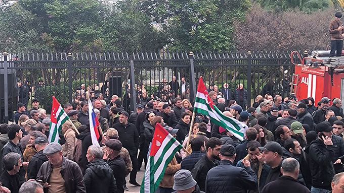 Protesty v Abcházii. Na snímku z 15. listopadu 2024 demonstranti mávají vlajkami před budovou parlamentu.