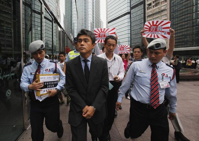 A representative (C) from the Japanese consulate is escorted by security guards carrying protest letters, as protesters follow behind, carrying Japanese Self-Defense Force flags demonstrate against Japan's decision to nationalise the islands, called Senkaku by Japan and Diaoyu by China, outside the Japanese Consulate in Hong Kong September 18, 2012. Japanese businesses shut hundreds of stores and plants and the country's embassy suspended services in China on Tuesday as anti-Japan protests reignited and risked dragging a territorial dispute between Asia's two biggest economies deeper into crisis. Chinese characters on the flags read, "Down with Japanese militarism". REUTERS/Bobby Yip (CHINA - Tags: POLITICS CIVIL UNREST TPX IMAGES OF THE DAY)