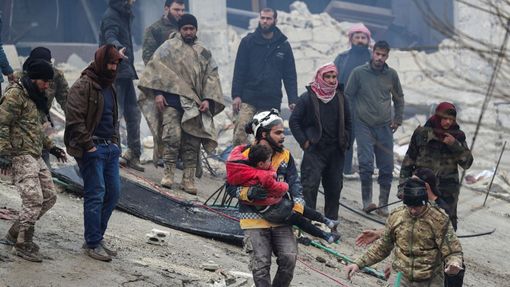 Záchranář nese dítě po zemětřesení v povstalci ovládaném městě Jandaris v Sýrii.
