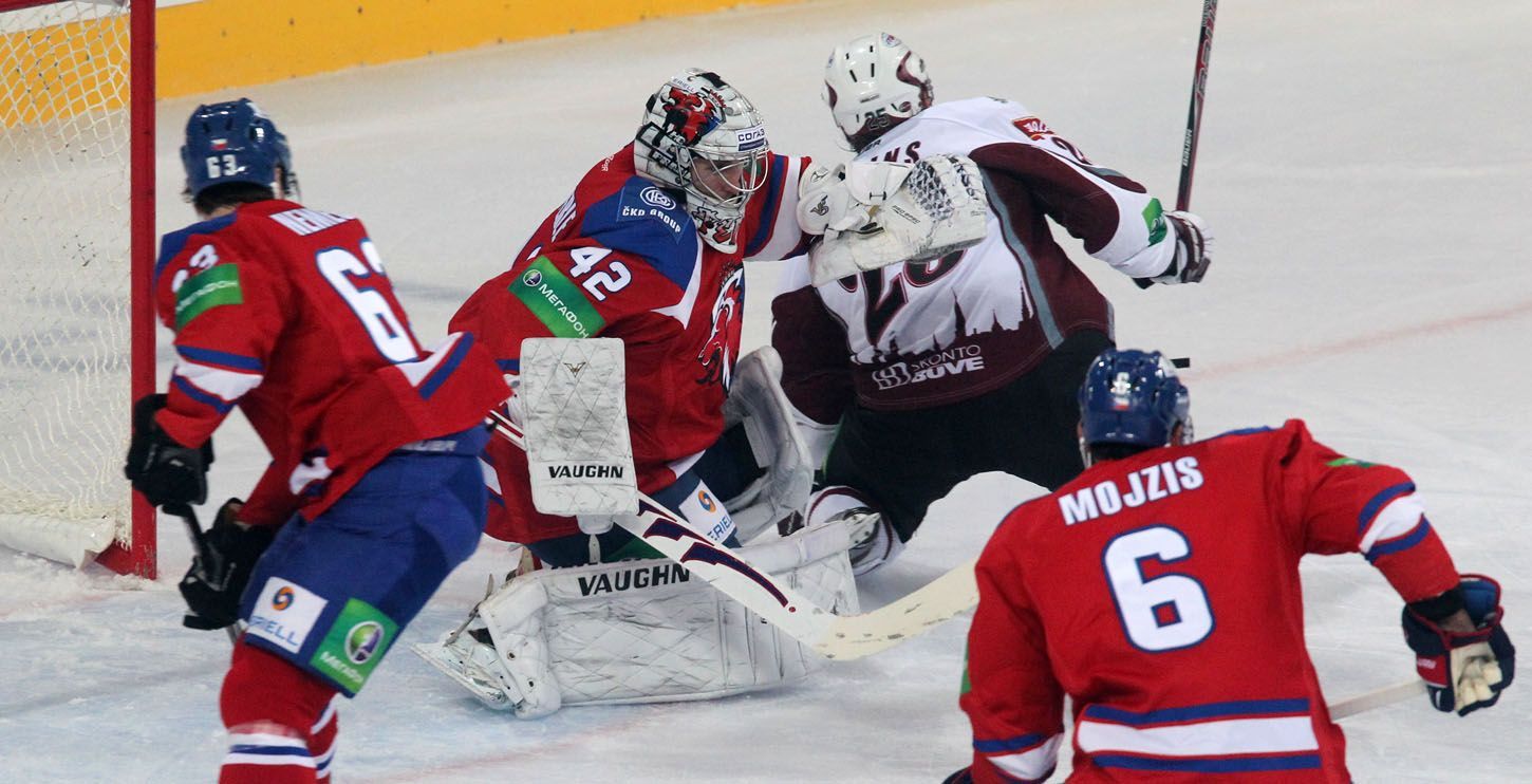 Hokejový brankář Tomáš Pöpperle zabraňuje gólu před Andrisem Džerinšem v utkání KHL 2012/13 mezi Lvem Praha s Dinamem Riga .