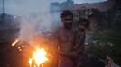 A man holds his child while standing next to burning coal to make it usable for domestic purposes such as for cooking at Dhanbad district in the eastern Indian state of Jharkhand September 19, 2012. With oil and gas output disappointing and hydropower at full throttle, Asia's third-largest economy still relies on coal for most of its vast energy needs. About 75 percent of India's coal demand is met by domestic production and, according to government plans, that won't change over the next five years. Picture taken September 19, 2012. To match INDIA-COAL/ REUTERS/Ahmad Masood (INDIA - Tags: BUSINESS EMPLOYMENT ENERGY SOCIETY ENVIRONMENT) Published: Říj. 21, 2012, 10:18 odp.