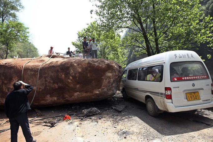 People stand near a van on a road blocked by a large rock after a strong 6.6 magnitude earthquake, at Longmen village, Lushan county, Ya'an, Sichuan province April 20, 2013. The earthquake hit a remote, mostly rural and mountainous area of southwestern China's Sichuan province on Saturday, killing at least 102 people and injuring about 2,200 close to where a big quake killed almost 70,000 people in 2008. REUTERS/Stringer (CHINA - Tags: DISASTER) CHINA OUT. NO COMMERCIAL OR EDITORIAL SALES IN CHINA Published: Dub. 20, 2013, 9:27 dop.