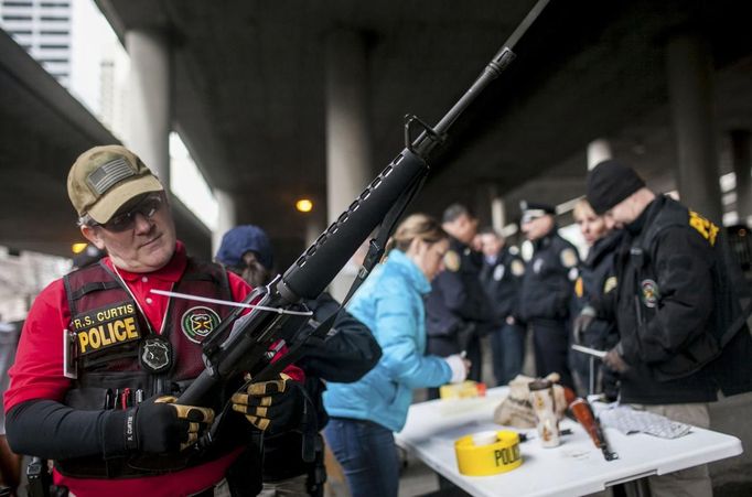 Seattle Police Officer R.S. Curtis looks over a M-16 that was turned in during a gun buyback event in Seattle, Washington January 26, 2013. Participants received up to a $100 gift card in exchange for working handguns, shotguns and rifles, and up to a $200 gift card for assault weapons. The event lasted from 9 a.m. until shortly after noon, after the event ran out of $80,000 worth of gift cards. REUTERS/Nick Adams (UNITED STATES - Tags: POLITICS CIVIL UNREST) Published: Led. 27, 2013, 2:22 dop.