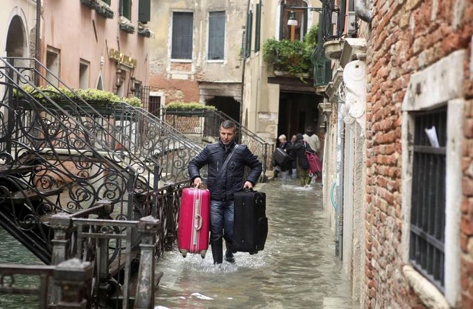 A person carry luggage in a flooded street during a period of seasonal high water in Venice November 1, 2012. The water level in the canal city rose to 140 cm (55 inches) above normal, according to the monitoring institute. REUTERS/Manuel Silvestri (ITALY - Tags: ENVIRONMENT SOCIETY) Published: Lis. 1, 2012, 12:57 odp.