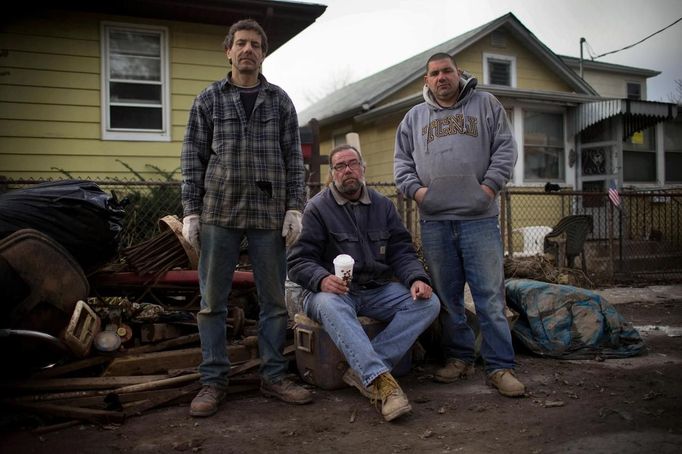 Friends (L-R) Joseph Ciavardone, Bobby Rasmussen and Carlo Loporto, who have been friends and neighbours since they where children living in New Dorp Beach, Staten Island, pose together as they take a break from gutting out the flooded remains of Ciavardone's home November 14, 2012. All three men had their homes completely flooded when Hurricane Sandy hit but they plan to stay in the area where they were born and raised. Picture taken November 14, 2012. REUTERS/Mike Segar (UNITED STATES - Tags: DISASTER ENVIRONMENT) ATTENTION EDITORS PICTURE 07 OF 19 FOR PACKAGE 'SURVIVING SANDY' SEARCH 'SEGAR SANDY' FOR ALL PICTURES Published: Lis. 20, 2012, 3:30 odp.