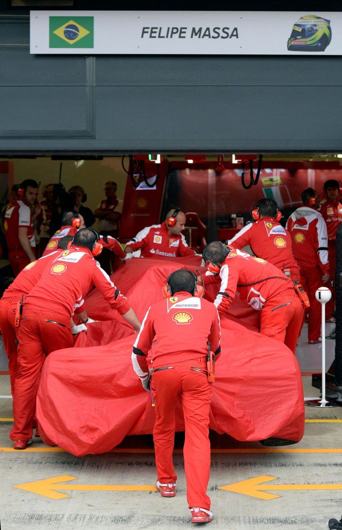 Engineers push the car of Ferrari Formula One driver Felipe Massa of Brazil to the pits after he crashed during second practice ahead of the British Grand Prix at the Sil