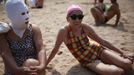 A woman, wearing a nylon mask, rests on the shore during her visit to a beach in Qingdao, Shandong province July 6, 2012. The mask, which was invented by a woman about seven years ago, is used to block the sun's rays. The mask is under mass production and is on sale at local swimwear stores. REUTERS/Aly Song (CHINA - Tags: SOCIETY ENVIRONMENT TRAVEL) Published: Čec. 6, 2012, 4:11 odp.