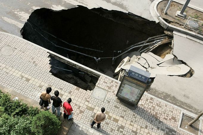 People look at a sinkhole People look at a sinkhole in a street in Taiyuan in north China's Shanxi province Thursday Aug. 12, 2010. Part of a hospital building beside it collapsed later but no one was killed in it.