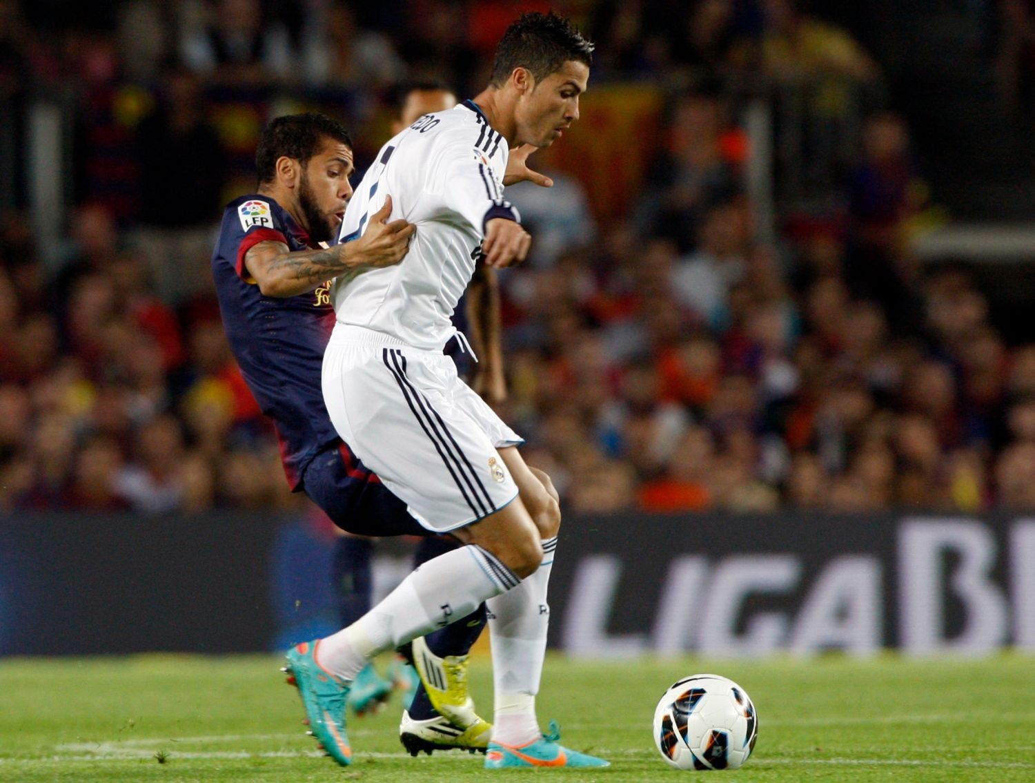Fotbalista Realu Madrid Cristiano Ronaldo v souboji s Dani Alvésem v utkání Primera División 2012/13 proti Barceloně.