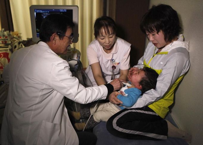 A doctor at a clinic in temporary housing complex Shunji Sekine (L) conducts a thyroid examination on a child in Nihonmatsu, about 50 km (31 miles) from the tsunami-crippled Fukushima Daiichi nuclear power plant, Fukushima prefecture February 25, 2013, ahead of the second-year anniversary of the March 11, 2011 earthquake and tsunami. As the World Health Organisation (WHO) says children in Fukushima may have a higher risk of developing thyroid cancer after the Daiichi nuclear disaster two years ago, mothers in Fukushima worry that local health authorities are not doing enough. Picture taken February 25, 2013. REUTERS/Chris Meyers (JAPAN - Tags: DISASTER HEALTH) Published: Úno. 28, 2013, 2:50 odp.