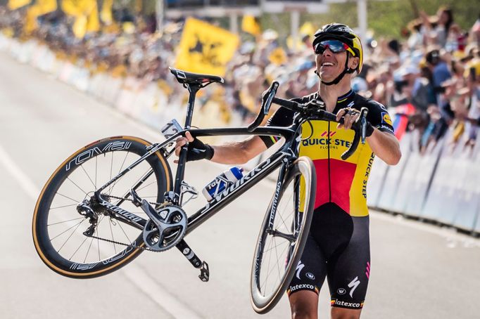 Belgický jezdec Philippe Gilbert (Quick-Step) prochází po nekonečném úniku jako vítěz cílem klasiky Kolem Flander a zvedá kolo nad hlavu.